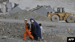 A family walks near an open cast mine in the Nangarhar region of eastern Afghanistan.