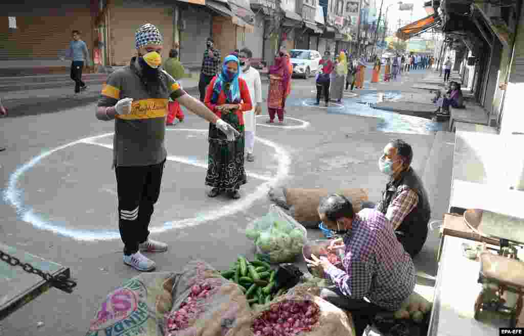 Луѓе во индискиот град Џаландхар стојат на одредените места за да одржат социјална дистанца додека чекаат да купат зеленчук.