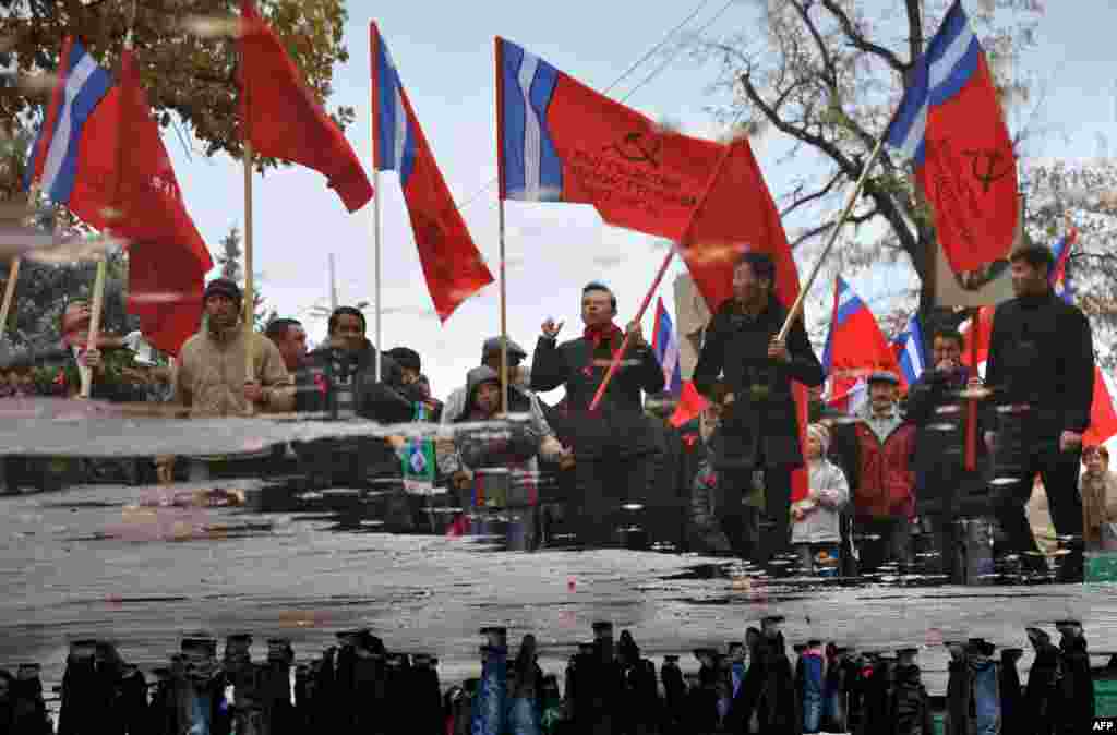 A rotated photo shows Kyrgyz communist party supporters holding their red flags, and portraits of the Soviet Union founder Vladimir Lenin, reflected in a puddle during a rally to mark the 97th anniversary of Russia&#39;s Bolshevik Revolution on November 7. (AFP/Vyacheslav Oseledko) 