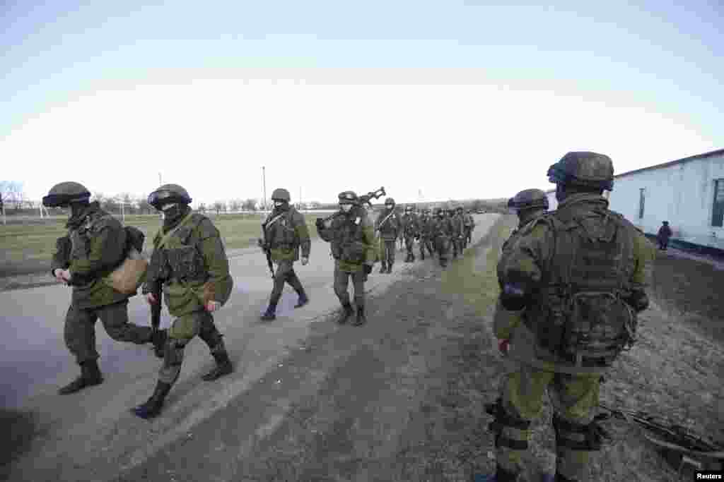 Military personnel, believed to be Russian servicemen, walk outside a Ukrainian military post in the village of Perevalnoye, near Simferopol.