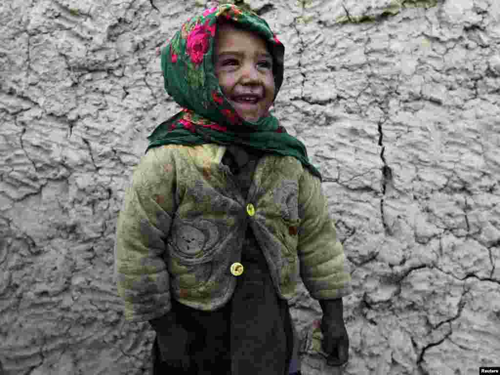 An internally displaced boy smiles in front of his residence in Kabul. Photo by Omar Sobhani for Reuters