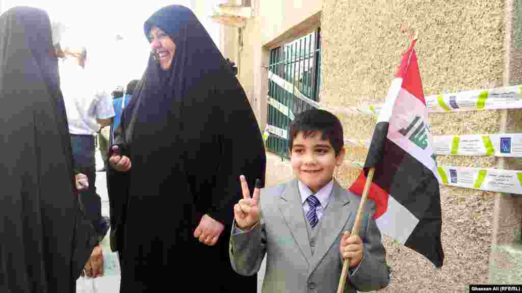 A boy with an Iraqi national flag and ink-stained finger after his mother casts her vote in Baghdad.