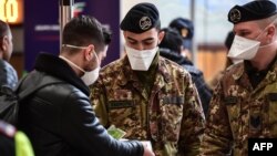 Войници проверяват документите на пътник преди той да се качи на влак от централната гара в Милано