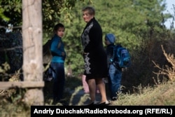 Misha, Stanislav, and their aunt Tetyana, stand in front of the bridge over the Kalmius River.