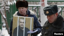 A man holds a portrait of jailed former oil tycoon Mikhail Khodorkovsky during a picket in support of Khodorkovsky outside the court building in Moscow where he was ordered to remain in jail until 2017.