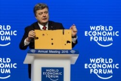 П’ятий президент України Петро Порошенко демонструє фрагмент пасажирського автобуса, який був знищений ракетним ударом російських гібридних сил на околиці Волновахи 13 січня 2015 року. Внаслідок атаки загинули 12 (за іншими даними 13) людей, ще 18 були поранені. Давос, 21 січня 2015 року