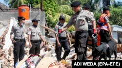 Pjesëtarë të policisë së Indonezisë duke kërkuar për ndonjë të mbijetuar pas tërmetit.