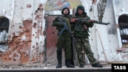 Members of the separatist "Somalia" Battalion pose outside a church riddled with bullets in Donetsk on November 13.