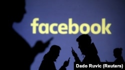 Силуэты людей с телефонами на фоне логотипа Facebook
