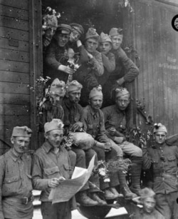 Polish troops being transported to the front line in boxcars. The troops were "decorated with flowers by Polish boys and girls as they passed."