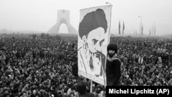 Шахқа қарсы шеру кезінде демонстранттардың бірі Рухолла Хомейнидің суретін ұстап тұр. Тегеран. 1978 жыл. 