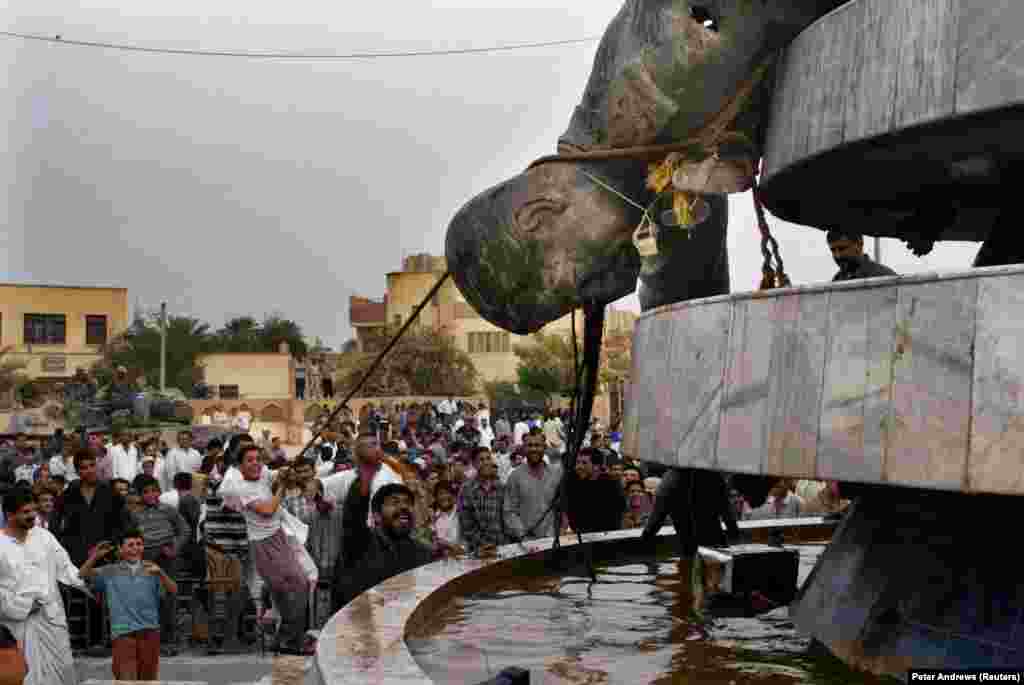 Иракчани влачат съборената статуя на иракския диктатор Садам Хюсеин в Кербала 18 дни след началото на войната в Ирак през 2003 г.&nbsp;