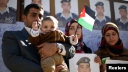 Родственники пилота Мааза аль-Касэсбеха с его портретами в руках