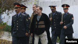 Pilots Aleksei Rudenko of Estonia (center, front) and Vladimir Sadovnichy of Russia (center, back) walk with guards during a break in an appeal hearing at a court in Kurgan-Tyube on November 22.