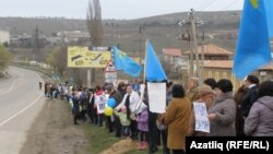 Женщины и дети стоят вдоль дороги в Крыму, держа в руках украинские и крымско-татарские флаги и плакаты с призывами к миру. 8 марта 2014 года.
