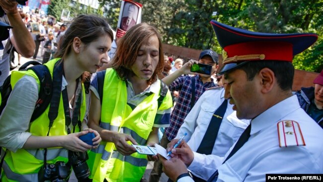Полицейские рассматривают документы журналистов во время шествия. В центре — корреспондент казахстанского издания Vlast.kz Данияр Молдабеков. Алматы, 9 мая 2019 года.