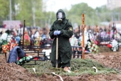 A gravedigger wearing a protective suit stands by a grave during the burial of a COVID-19 victim on the outskirts of Moscow on May 15.