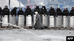 A woman walks in front of riot police on Hrushevskyy Street in central Kyiv.