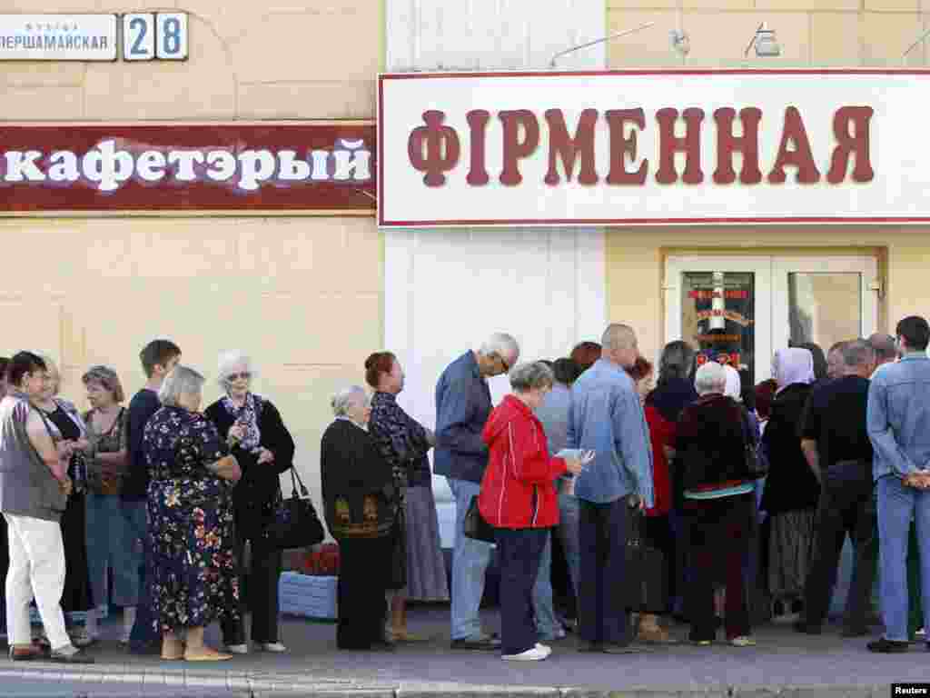 People wait in a line to buy meat in front of the closed door of a shop before it opens in Minsk on August 26. 