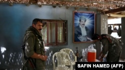 Members of the Kurdistan Workers' Party (PKK) rest in front of a portrait of jailed Kurdish rebel chief Abdullah Ocalan at a camp on July 29, 2015 deep in the Qandil mountain, the PKK headquarters in northern Iraq.