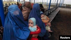 Afghan refugee women sit with their babies as they wait with others to be repatriated to Afghanistan at the UNHCR office on the outskirts of Peshawar in February.