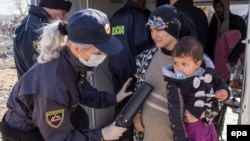 A Macedonian police officer checks a woman and her child with a metal detector near the Macedonian town of Gevgelija after they crossed the border from Greece on March 2.
