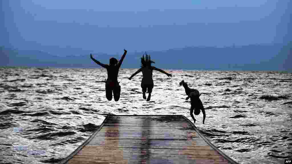 Three girls jump in Lake Ohrid in Macedonia on July 12. A heat wave in Macedonia with temperatures over 40 degrees Celsius forced residents to seek relief in the rivers and lakes. (AFP/Robert Atanasovski)