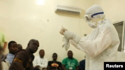 Медицина кызматкери эболадан коргонууну жергиликтүү тургундарга үйрөтүүдө.