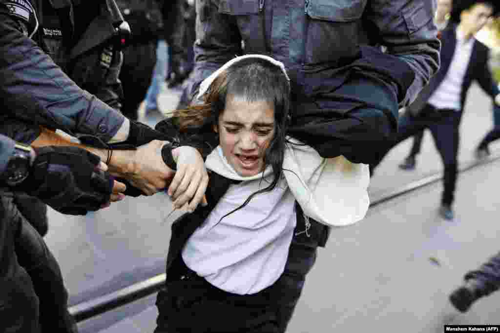 Israeli security forces grab an ultra-Orthodox Jewish boy who was among demonstrators in Jerusalem against Israeli Army conscription. Many ultra-Orthodox Jews oppose military service because they believe it exposes soldiers to influences and temptations not found in the insular world of prayer and religious study. (AFP/Menahem Kahana)