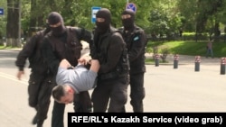 Сотрудники полицейского спецназа несут задержанного на несанкционированной акции протеста. Алматы, 10 мая 2018 года.