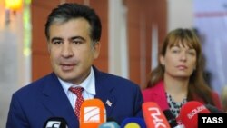 Georgian President Mikheil Saakashvili (left), accompanied by his wife, Sandra Roelofs, speaks to journalist during parliamentary elections at a polling station in Tbilisi on October 1.