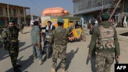 Afghan security personnel stop people as they block the road near the U.S. military base in Bigram some 50 km north of Kabul on November 12.