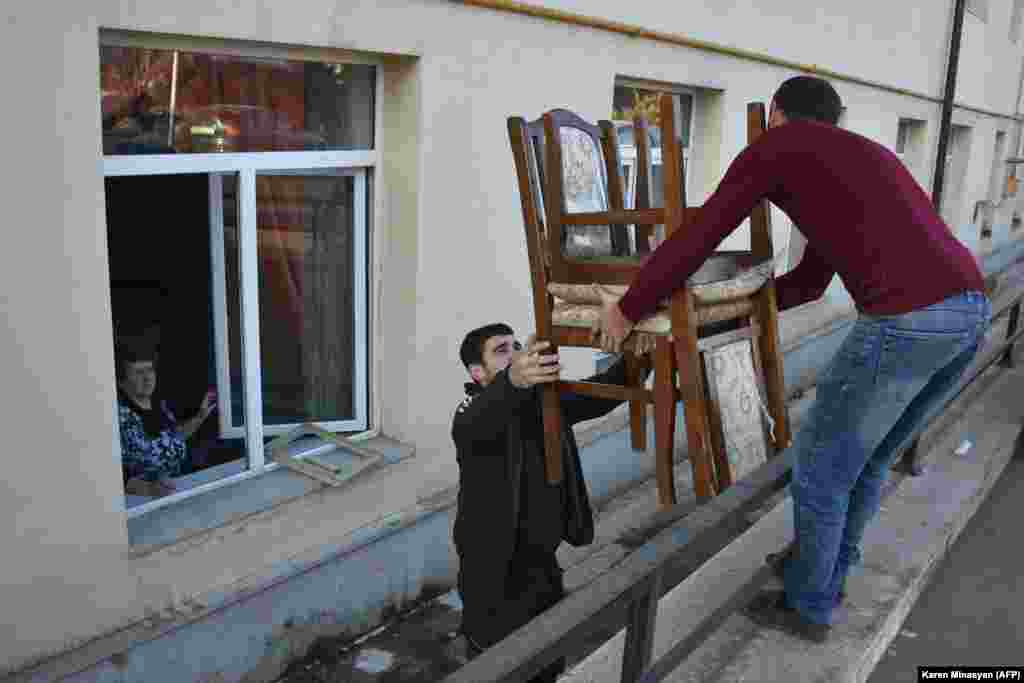 Жители Степанакерта заносят мебель в дом после возвращения.