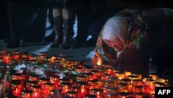 A woman lights a candle at the monument to victims of the Holodomor in Kyiv.