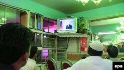 Afghans watch the debate at a shop in Kabul.