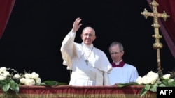 Pope Francis gestures to crowds at St. Peter's Basilica in Rome following Easter Sunday Mass on March 27.