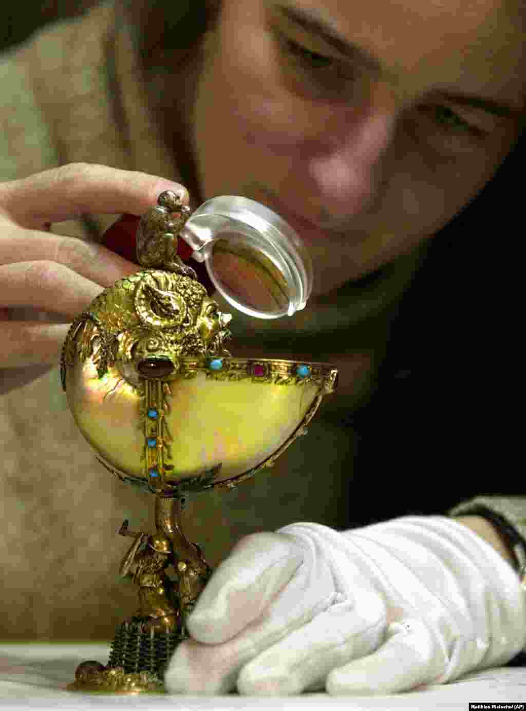 A restorer inspects a "Nautilus Cup" dating from 1570. It's made of ivory, rubies, silver, and gold.