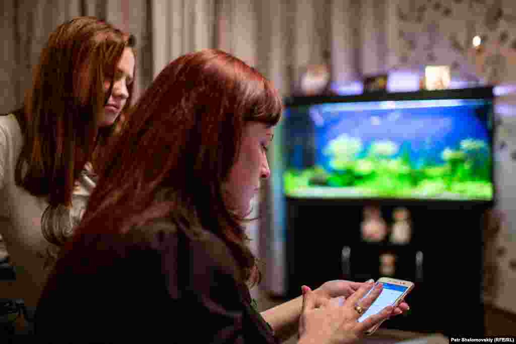 Konstantin Momot's wife and stepdaughter in their Vorkuta apartment. Momot's wife, Svetlana, says he loved to spend hours maintaining the 300-liter fish tank that dominates the apartment's living room.