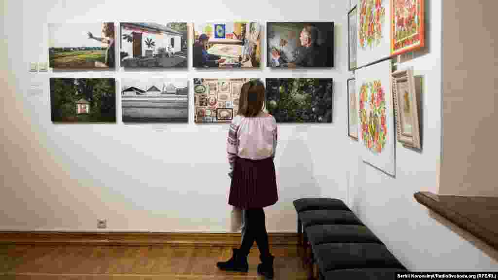 Дівчина розглядає фотографії з проекту про Петріківку авторства Марії Савоскули та Сергія Коровайного