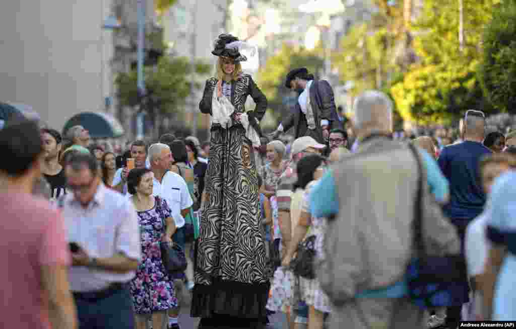 Entertainers on stilts stand above crowds in downtown Bucharest.&nbsp;(AP/Andreea Alexandru)