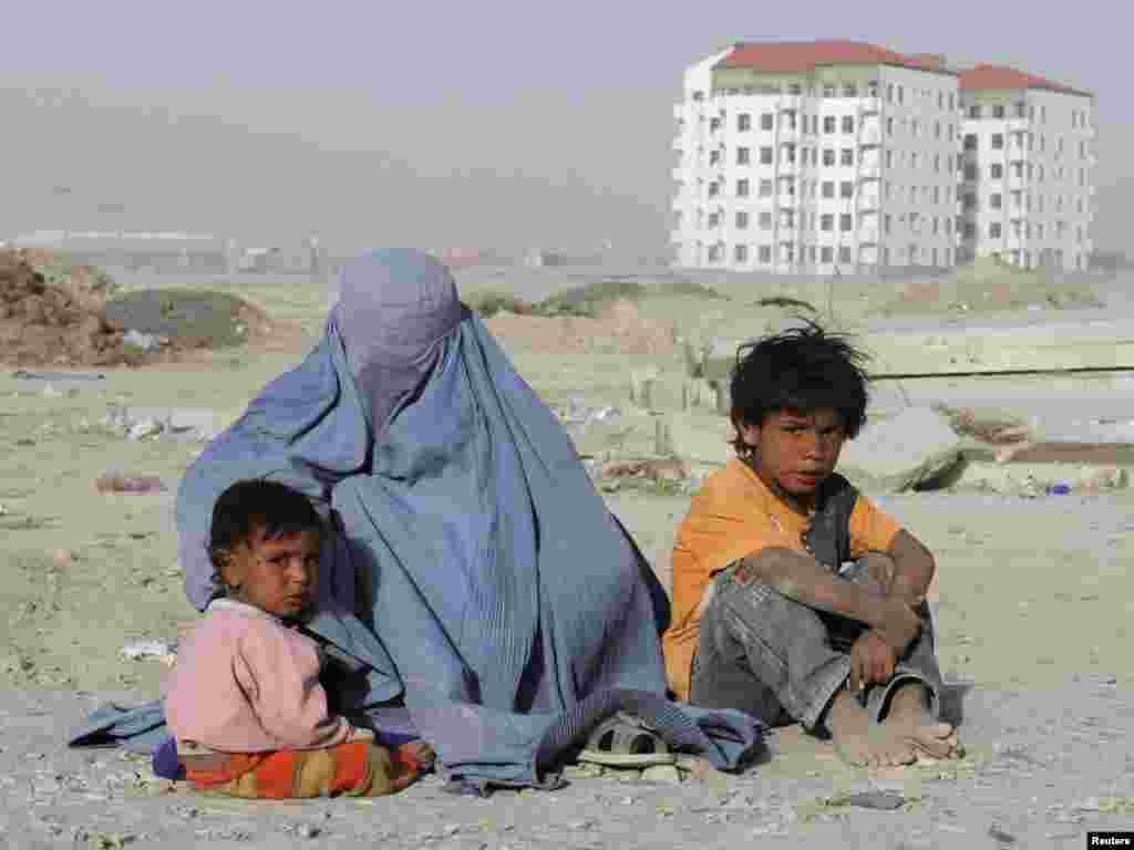 An Afghan woman dressed in a burqa begs with her children near a newly constructed building in Kabul on June 14. Photo by Mohammad Ismail for Reuters