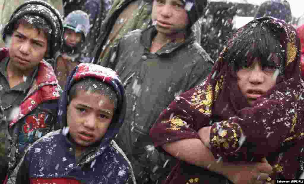 Children wait in the snow at a camp for displaced people in Kabul.