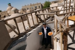 A waiter emerges from a restaurant with plates of Uzbekistan’s famed plov in 2016.