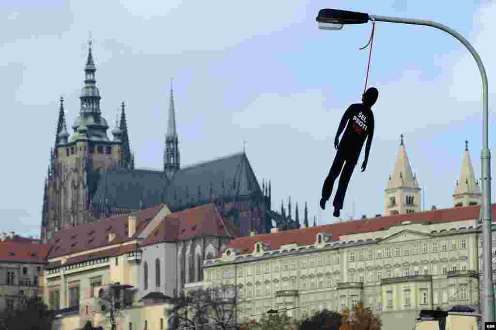 A hanged dummy with "Was against the Communist Party" written on it blows in the wind with the Prague Castle in the background on October 22.
