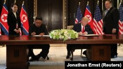 АҚШ президенті Дональд Трамп пен Солтүстік Корея басшысы Ким Чен Ын кездесу қортындысы бойынша құжатқа қол қойып отыр. Сентосa аралы, Сингапур. 12 маусым, 2018 жыл