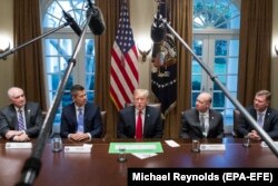 ABŞ-yň prezidenti Donald Tramp (ortada) žurnalistleriň öňünde çykyş edýär.
