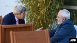 جان کری، وزیر امور خارجه آمریکا در حال گفتگو با محمدجواد ظریف، همتای ایرانی‌اش