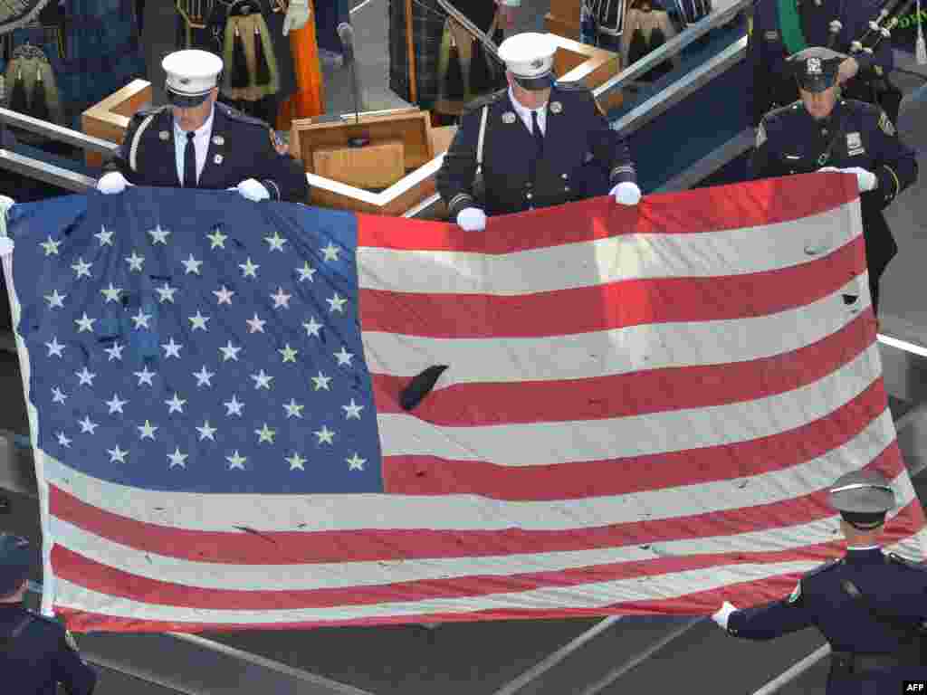 A U.S. flag recovered from the 9/11 attacks is displayed by New York City Police officers and firefighters during the ceremony marking the 10th anniversary of the terrorist attack.