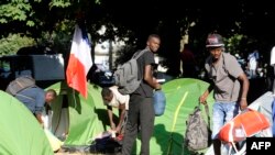 Migrants and refugees leave their camp as they are evacuated by French CRS riot police in Nantes, western France, on July 23.