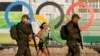 Special military police pass the Olympic rings next to morning joggers during the Rio 2016 Olympic Games, on Copacabana Beach in Rio de Janeiro. (epa/Barbara Walton)